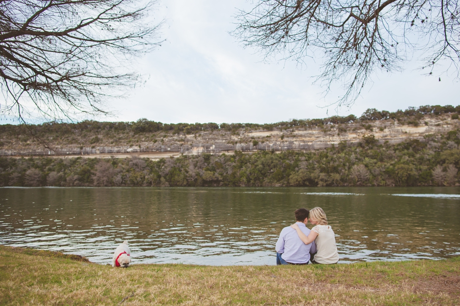 engaged couple snuggling near water with dog in austin