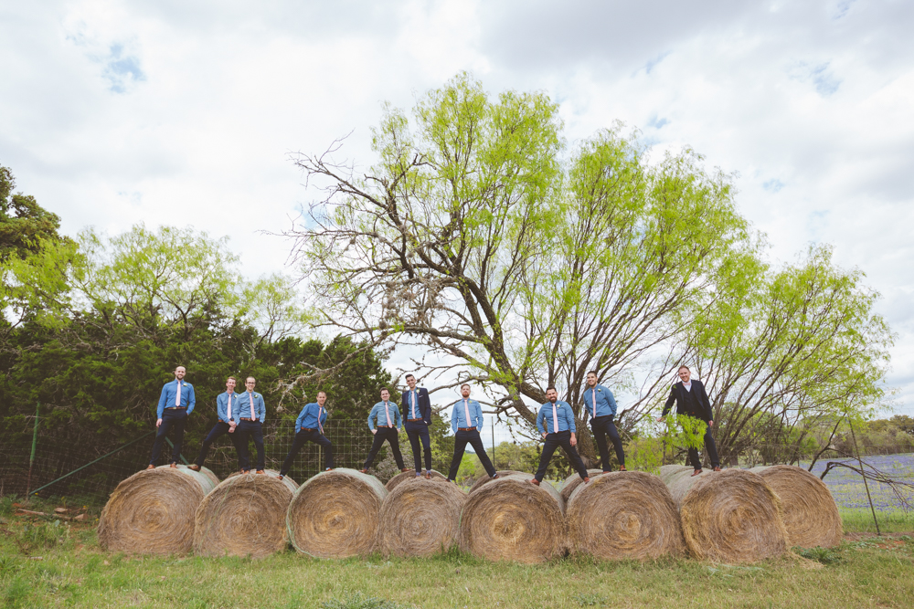 groomsmen standing on hay bales