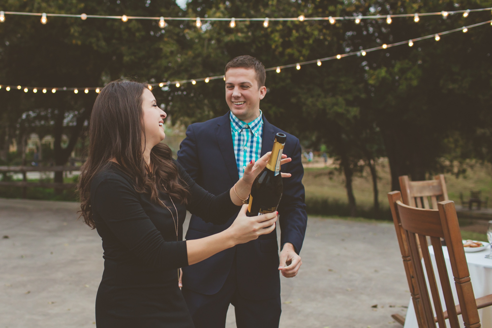 newly engaged couple popping champagne