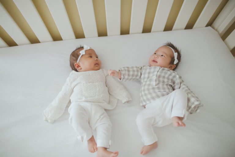 twin baby girls playing in crib