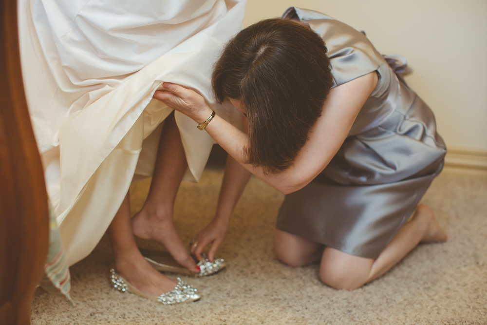 mom helping bride with shoes
