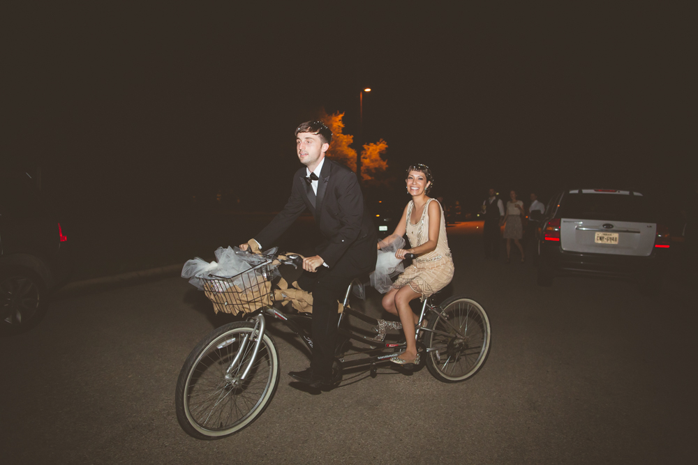 bride and groom exit on tandem bicycle