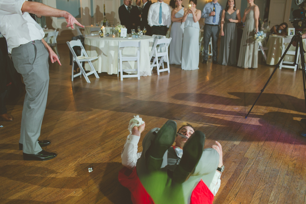 groomsman in a cape doing a flip to catch the garter