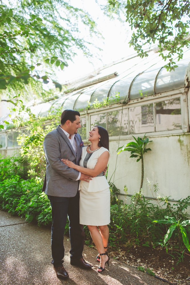 bride and groom laughing in front of a greenhouse
