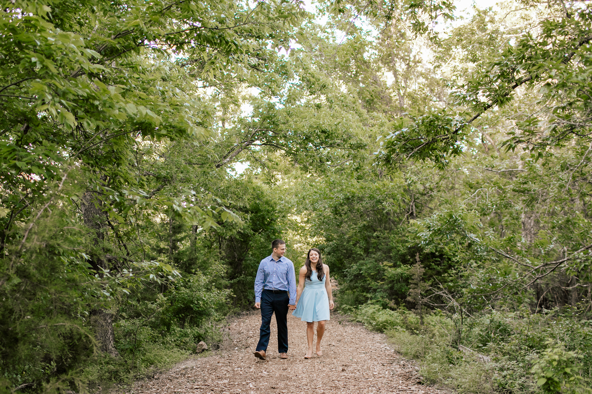 engaged couple walking in the woods