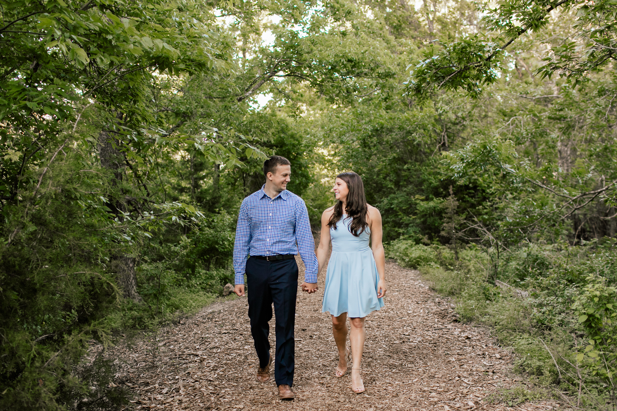 engaged couple walking in the woods