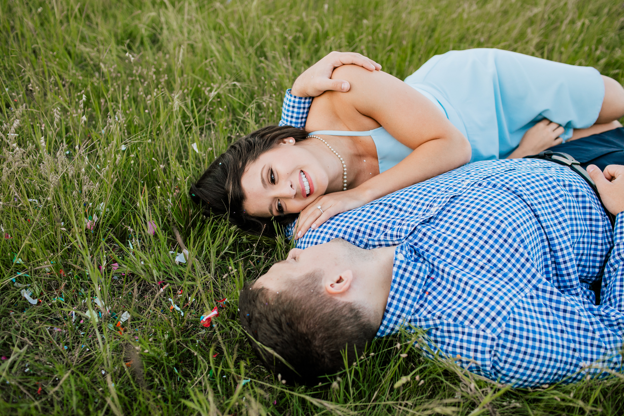 engaged couple laying in the grass