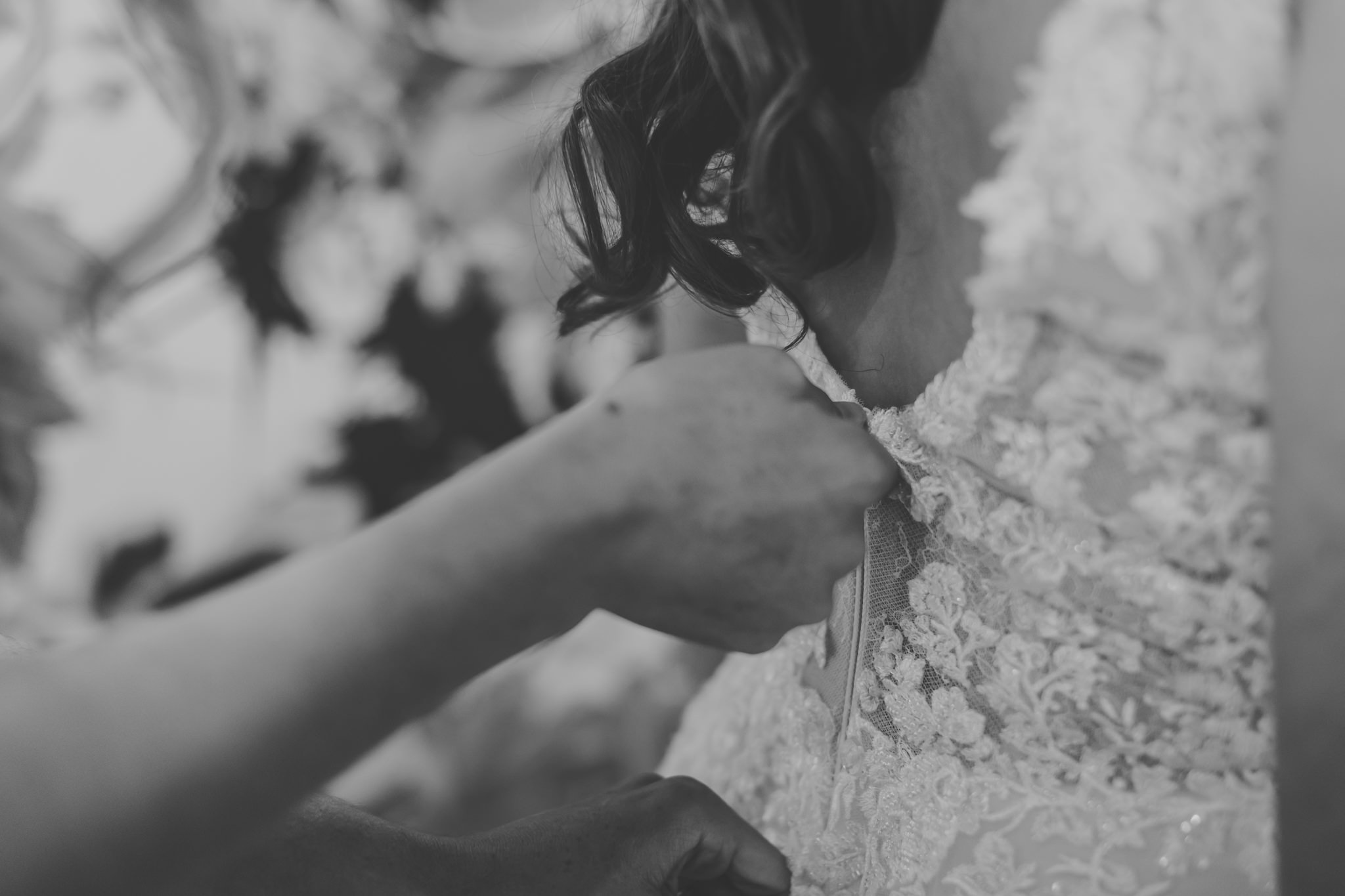 bride's dress getting zipped up