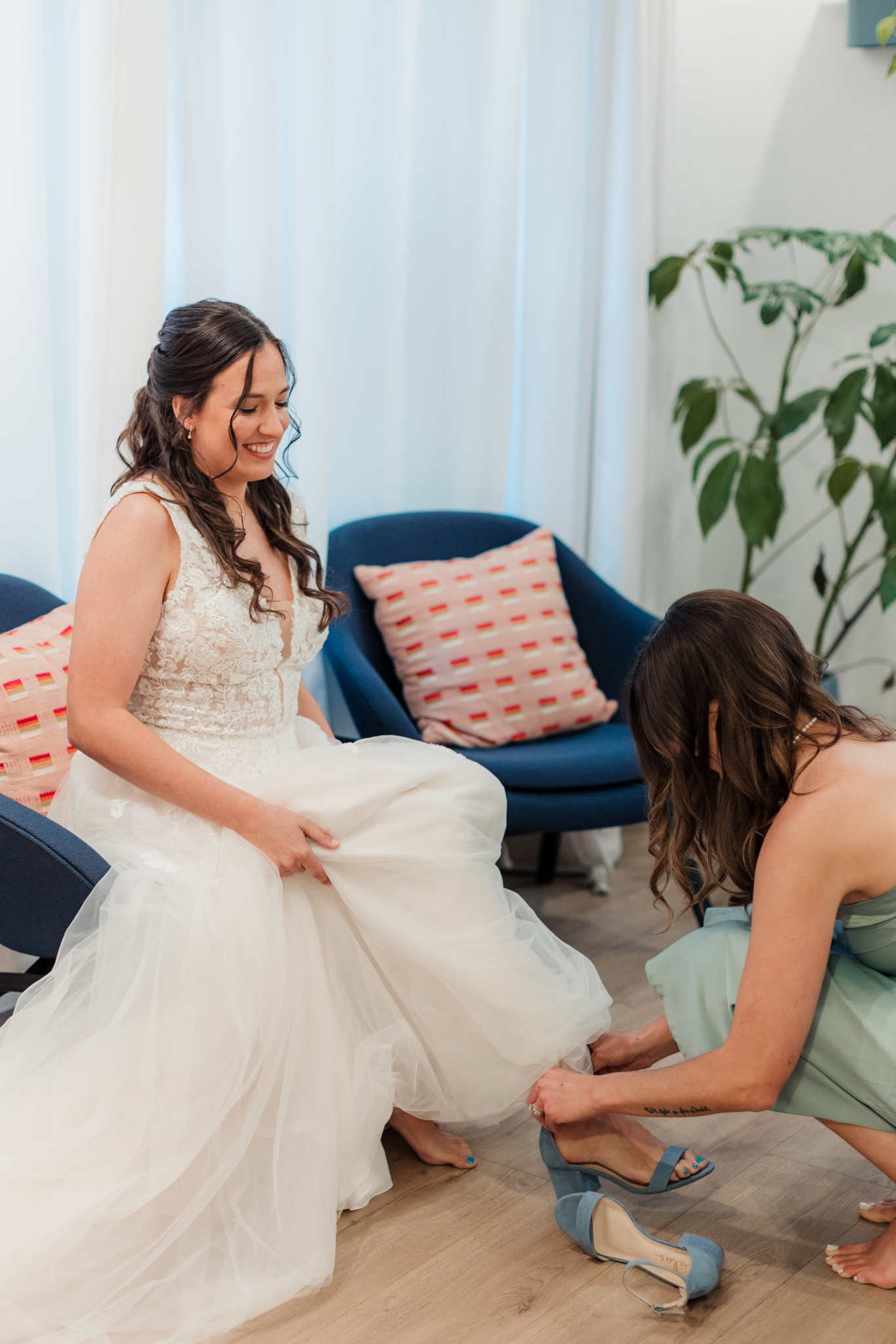 bride getting ready while sister puts her shoes on