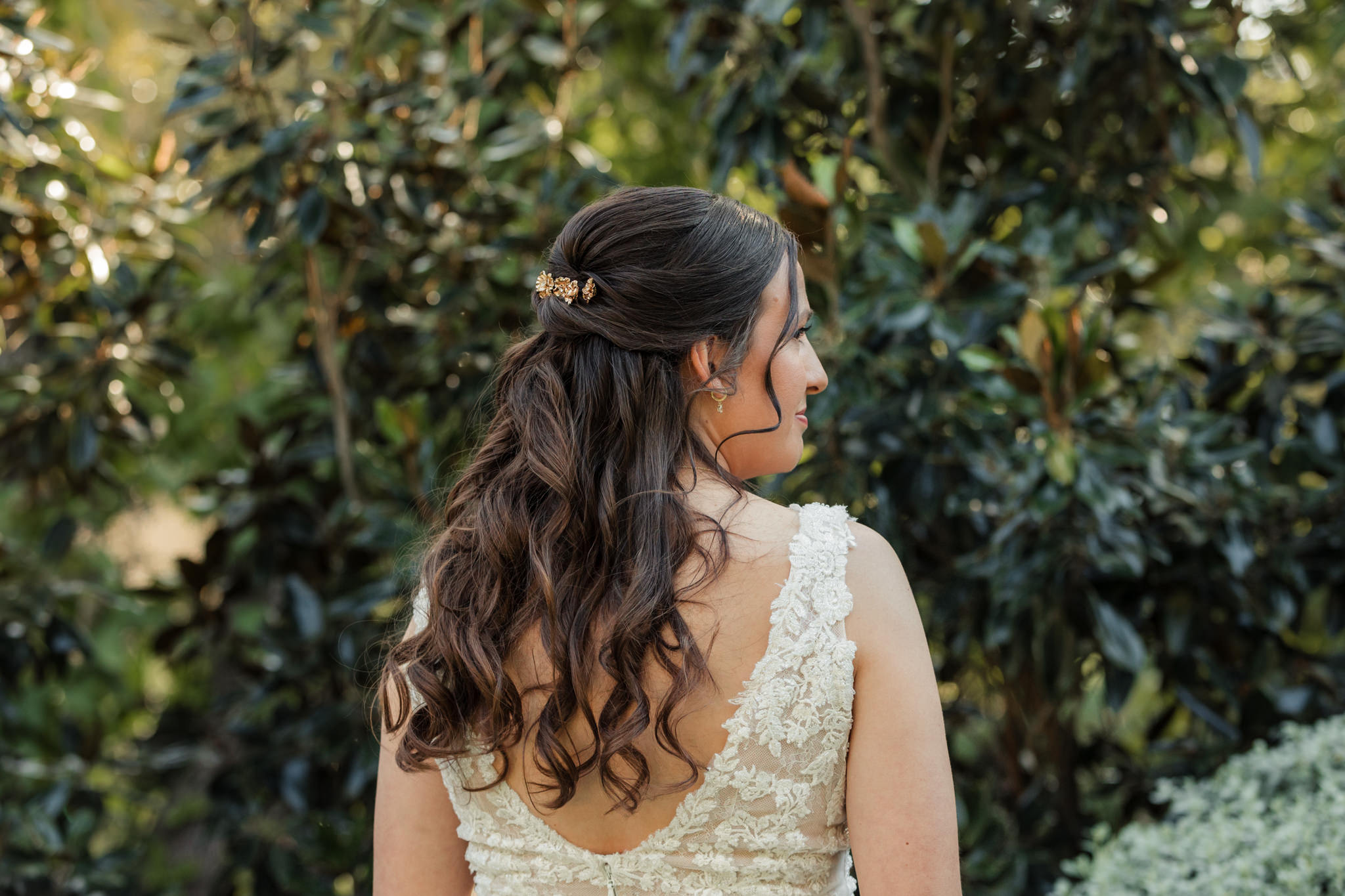 details of bride's hair curled and half up with a decorative clip