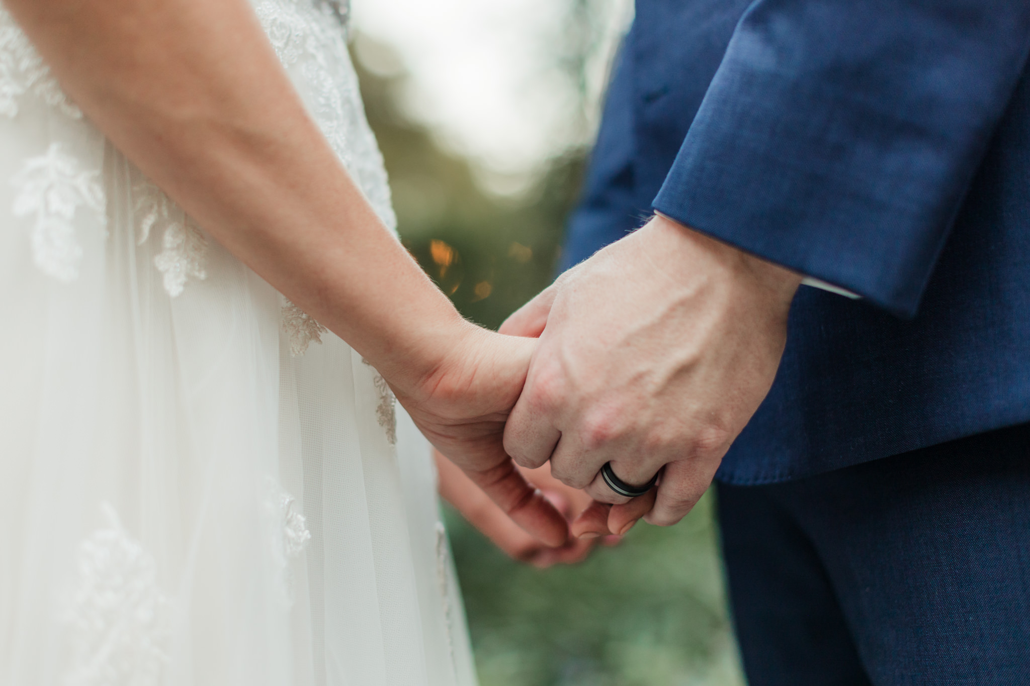 close up of groom's ring holding hands