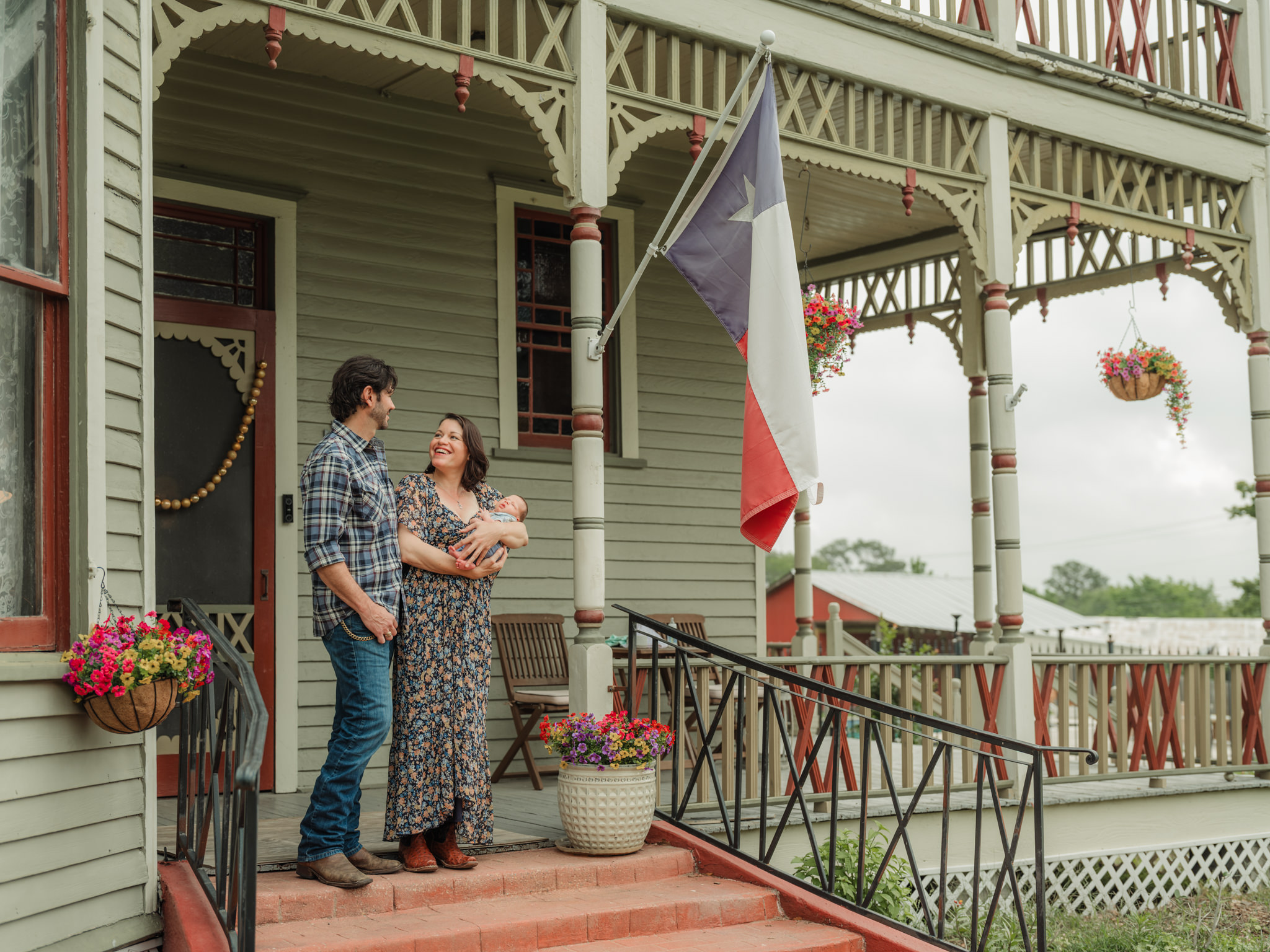 standing with baby on the porch with a Texas flag