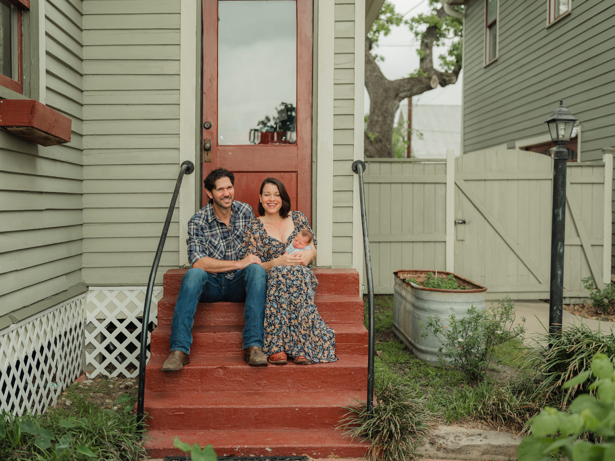 family sitting with newborn on the porch steps